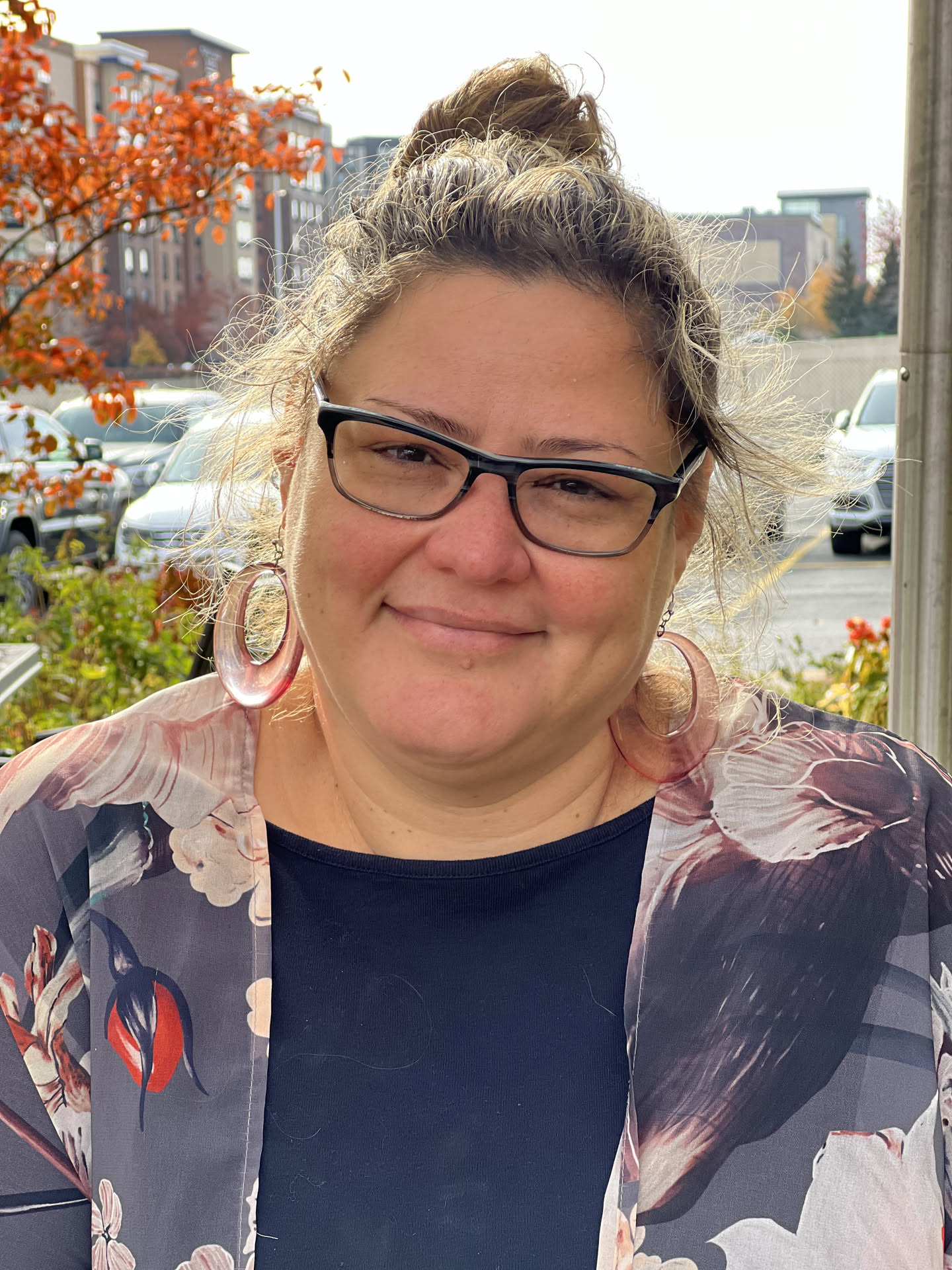Fayemarie in glasses and hoop earrings with autumn leaves behind