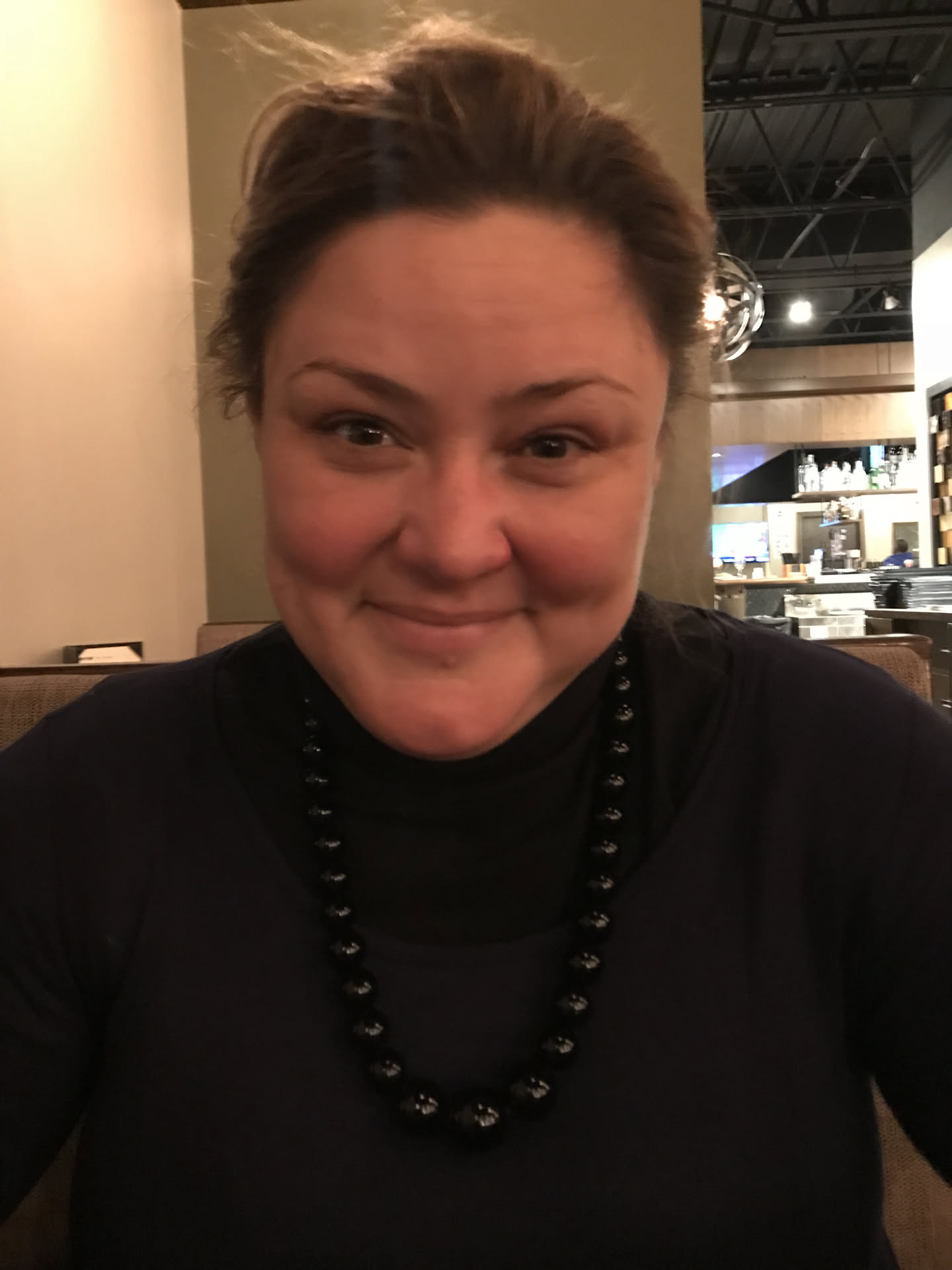 Fayemarie in a black top and beaded necklace